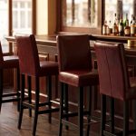 Chaises de bar CHR en hêtre wengé et similicuir brun devant le comptoir d'un café