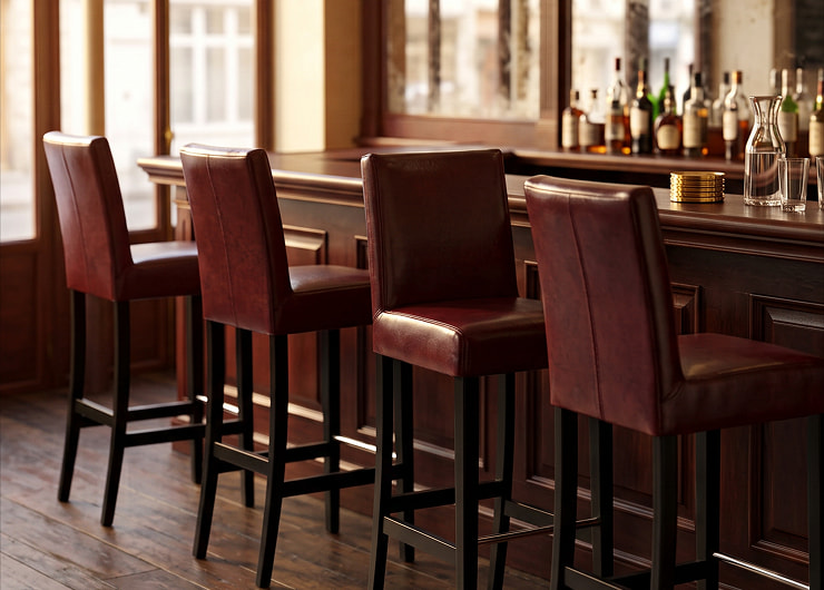 Chaises de bar CHR en hêtre wengé et similicuir brun devant le comptoir d'un café