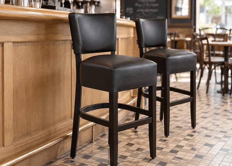 Chaises de bar CHR en hêtre et similicuir noir le long d'un comptoir de café