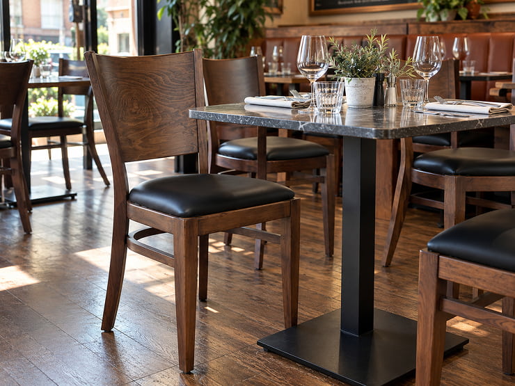 Chaises de restaurant en hêtre et similicuir dans une salle dressée
