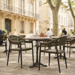 Chaises de terrasse en rotin synthétique vert autour de tables sur une terrasse de restaurant